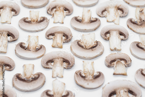 sliced champignons mushrooms on a white background arranged as a pattern