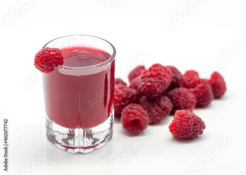 glass with raspberry alcoholic drink and raspberries on white background 