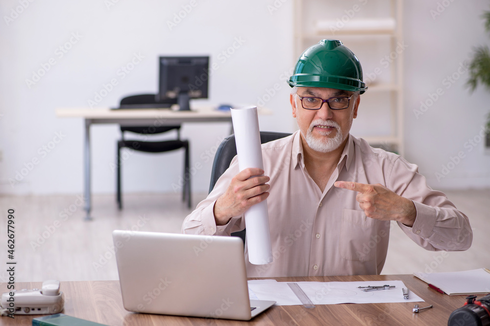 Old male architect working in the office Old male architect working in the office