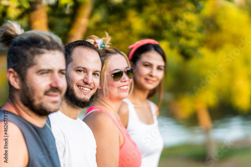 Selective focus on a man with beard standing with a group of friends in a park