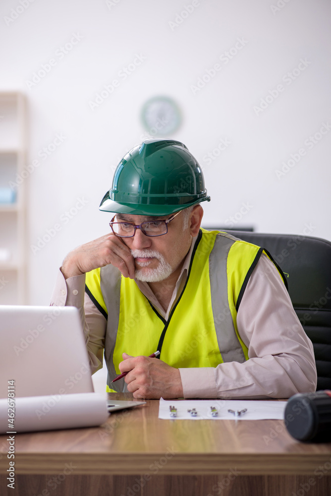 Old male architect working in the office Old male architect working in the office