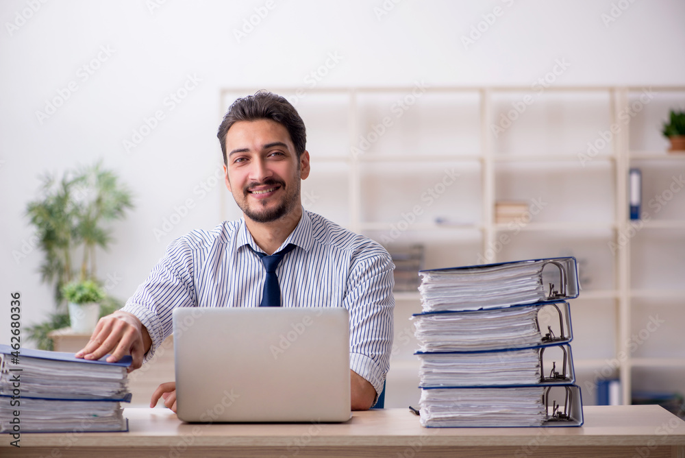 Young male employee and too much work in the office Young male employee and too much work in the office