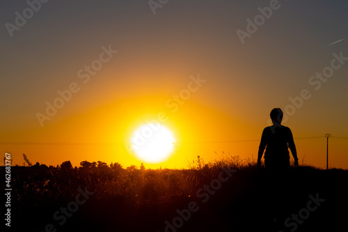 Silhouette of a woman walking in the field at sunset. Rural life. Sunset walks