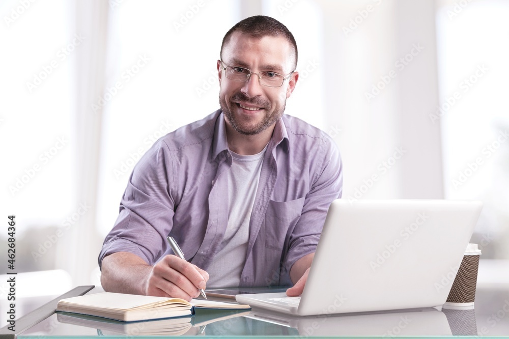 Human sitting at desk and writing down notes on a notebook Human sitting at desk and writing down notes on a notebook