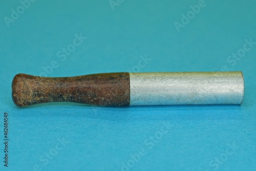 one old long brown white smoking mouthpiece lies on a blue table