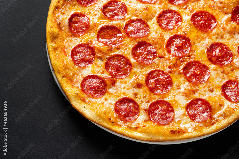 Tasty pepperoni and tomatoes on black background Tasty pepperoni and tomatoes on black background