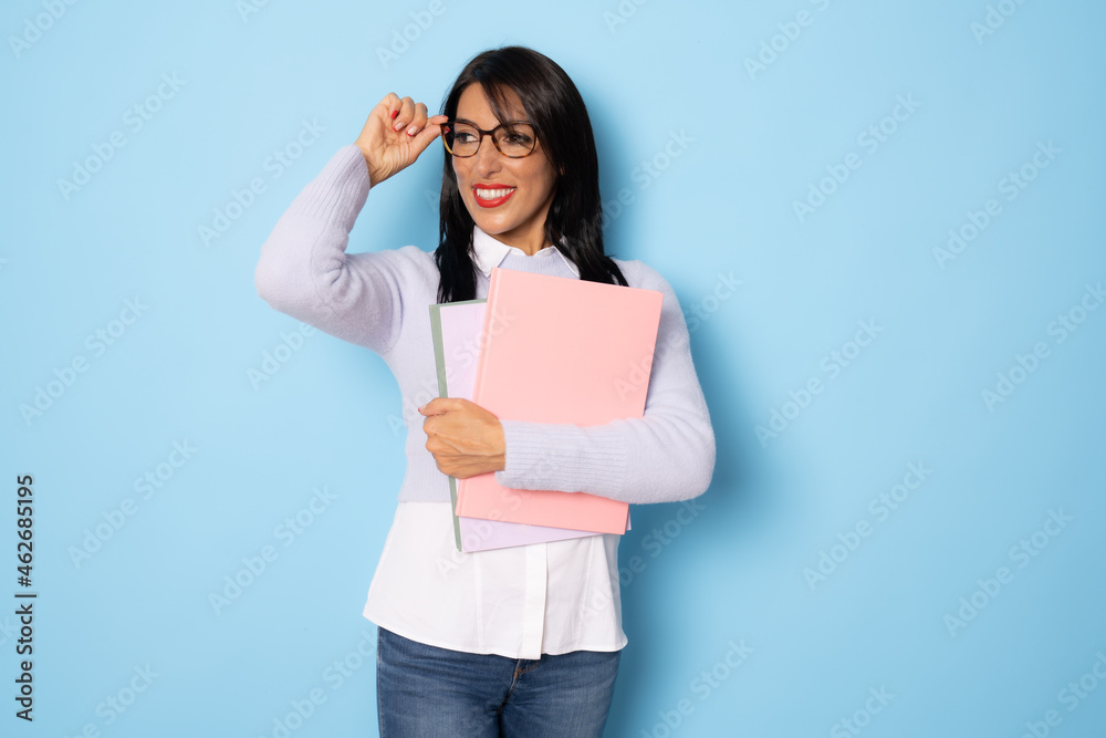 Smiling woman holding books. isolated portrait of school teacher isolated over blue background. Smiling woman holding books. isolated portrait of school teacher isolated over blue background.