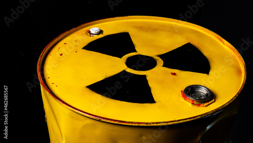 Yellow metal barrel with radioactive decay symbol on top. Container with nuclear trefoil warning sign. Drum with toxic hazardous waste. Disposal, utilization problem. Environmental harm