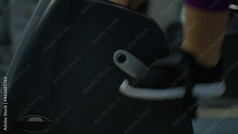 Close-up stationary exercise bike pedals with plus-size female feet cycling. Unrecognizable Caucasian overweight woman exercising on equipment in gym indoors. Aerobics and fitness concept Close-up stationary exercise bike pedals with plus-size female feet cycling. Unrecognizable Caucasian overweight woman exercising on equipment in gym indoors. Aerobics and fitness concept