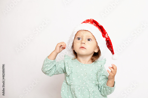 Portrait of a cute girl with blue eyes in a Christmas cap. White background, space for text. New Year