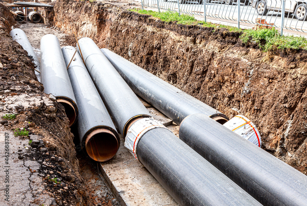 Construction works on large iron pipes at a depth of excavated trench Construction works on large iron pipes at a depth of excavated trench