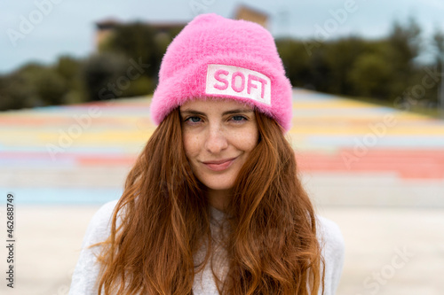 Portrait of redheaded woman wearing pink cap with the word 'soft'