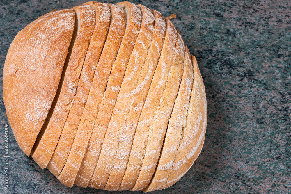 a round loaf of sliced wheat bread with a baked shiny crust on the kitchen table a round loaf of sliced wheat bread with a baked shiny crust on the kitchen table