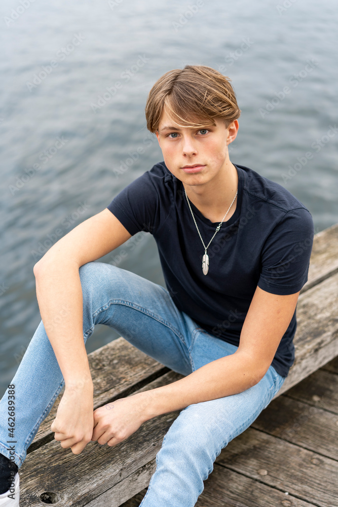 Denmark, Copenhagen, portrait of young man sitting at the waterfront Denmark, Copenhagen, portrait of young man sitting at the waterfront