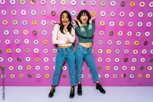 Two young women screaming at an indoor theme park with donuts at the wall