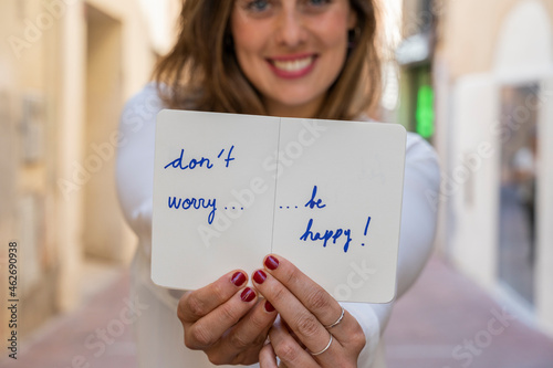 Portrait of smiling woman, holding notebook: Don't worry be happy! photo