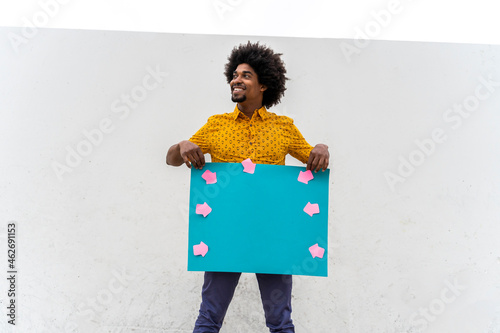 Young man wearing yellow shirt, blue indicating label with arrow signs