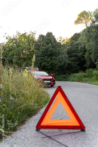 Warning triangle in front of a broken car on a country road photo