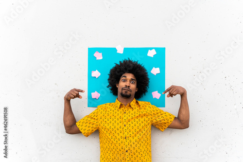 Young man wearing yellow shirt, blue indicating label with arrow signs