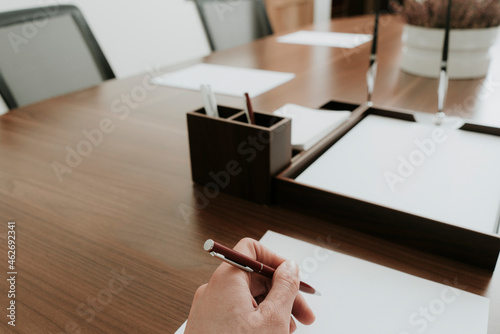 Hand holding ballpen at conference table in office photo