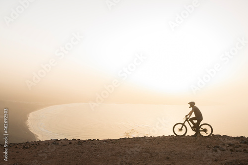 Spain, Lanzarote, mountainbiker on a trip at the coast at sunset
