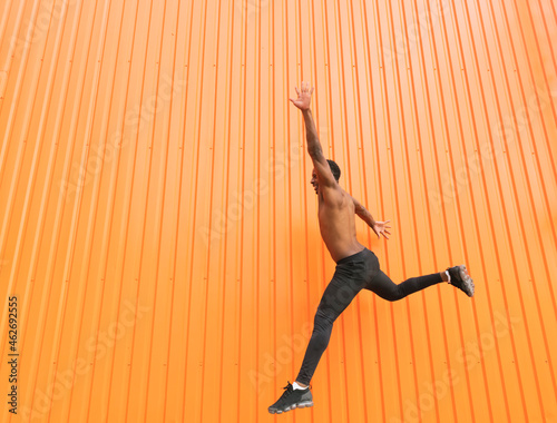 Athlete jumping in front of an orange wall