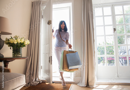 Woman with shopping bags, coming through front door photo