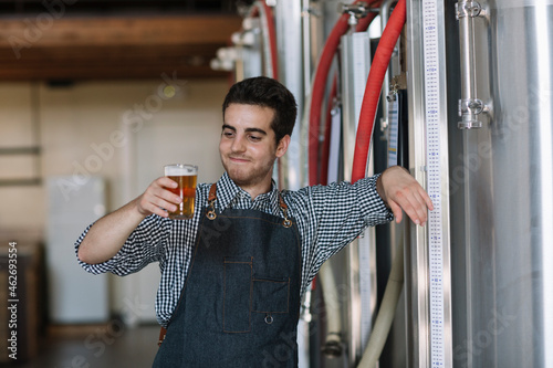 Portrait of confident young man holding beer glass at a brewery photo