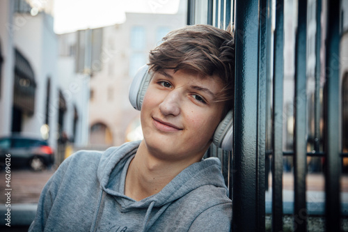 Portrait of teenager with headphones, sitting on steps in the city