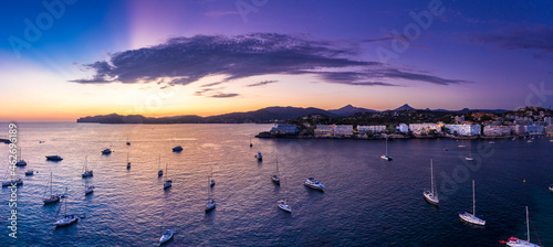 Spain, Mallorca, Santa Ponsa, Aerial panorama of boats floating in coastal water at purple dusk with town in background photo
