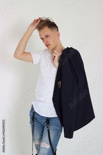 Handsome young fashion male model posing with jacket over his shoulder.