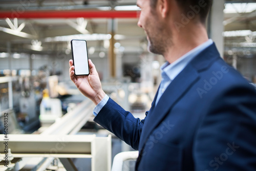 Businessman using cell phone in factory photo