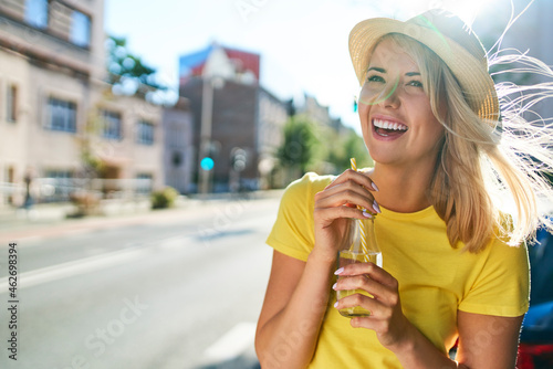 Happy young woman enjoying a drink in the city photo