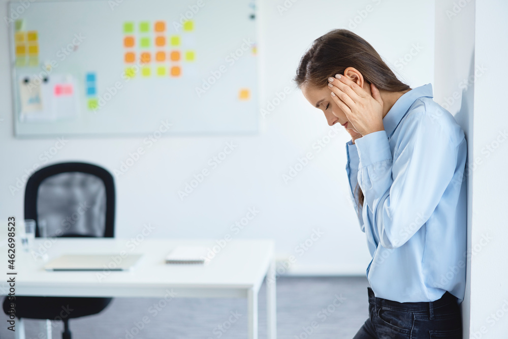 Young businesswoman suffering from headache in office