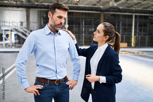 Businesswoman talking to disappointed businessman in a factory photo