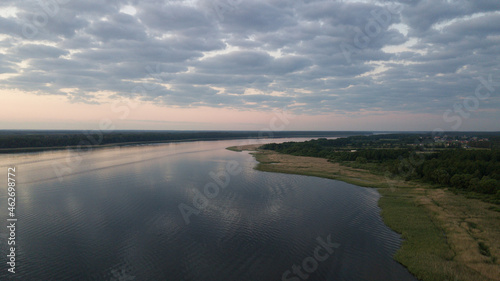 Aerial view of the lake  green forest and fields. Cumulus clouds in the background.