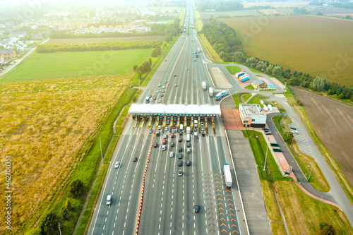 An overhead view of a busy toll road with many cars queuing up to pay the highway toll