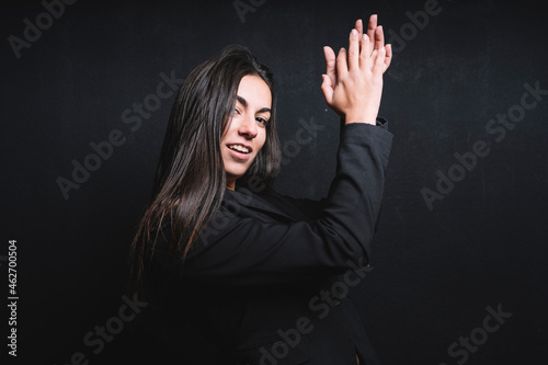 Portrait of smiling young woman clapping her handst in front of black background photo