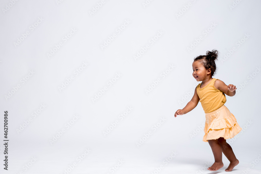 Happy little girl running barefoot in front of grey background Happy little girl running barefoot in front of grey background
