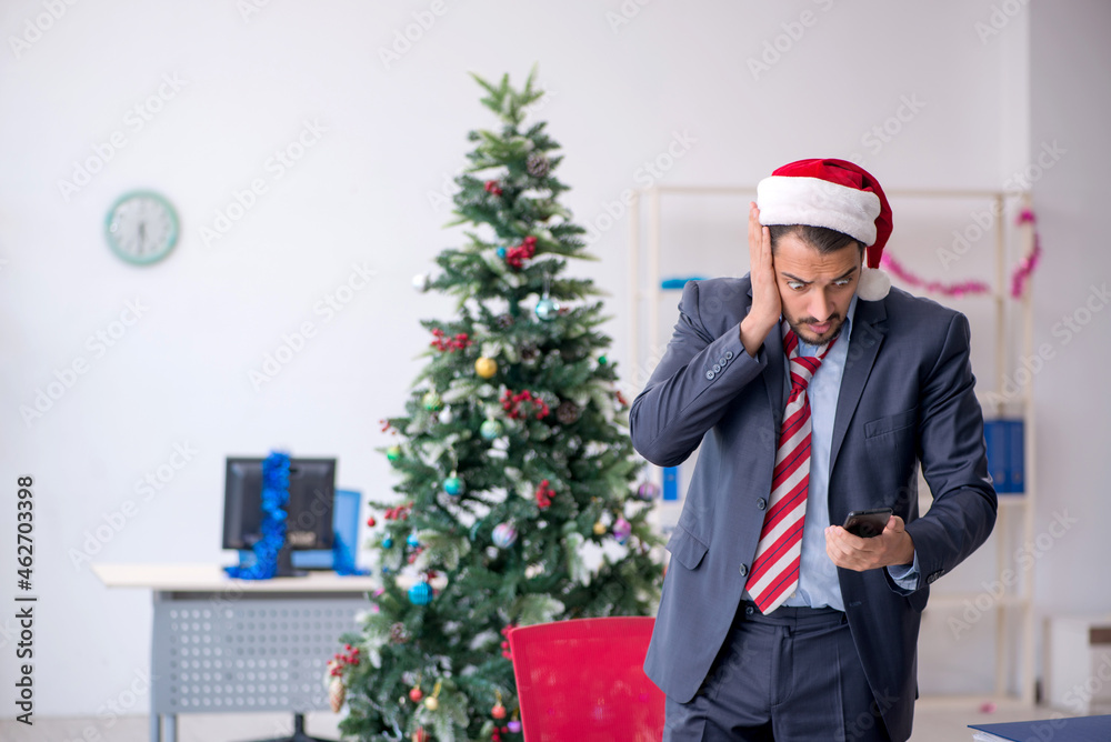 Young male employee celebrating Christmas at workplace Young male employee celebrating Christmas at workplace