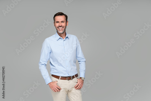 Fototapeta Photo of a smiling formal business man wearing a light blue shirt,  standing and