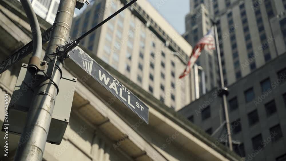 Wall Street sign with American flags in the background, shot in the heart of the business world in Manhattan. Business, finance, worldwide stock trade and economics concept. Wall Street sign with American flags in the background, shot in the heart of the business world in Manhattan. Business, finance, worldwide stock trade and economics concept.