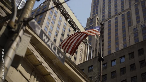 Wall Street sign with American flags in the background, shot in the heart of the business world in Manhattan. Business, finance, worldwide stock trade and economics concept.