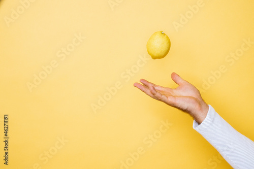 Studio shot of hand of person tossing up lemon photo