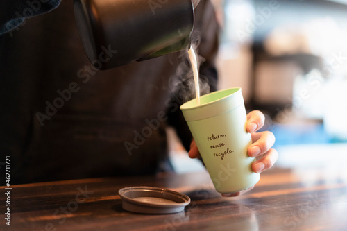 Man pouring hot milk into deposit cup for Coffee to go, close-up photo