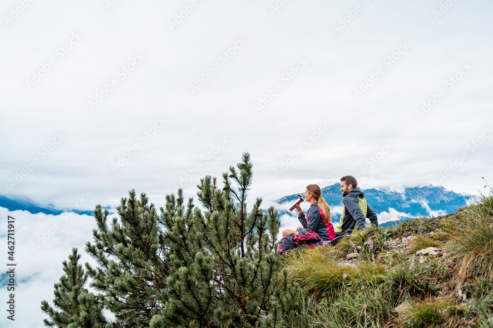 Young couple on a hiking trip in the mountains having a break, Herzogstand, Bavaria, Germany Young couple on a hiking trip in the mountains having a break, Herzogstand, Bavaria, Germany