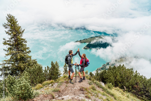 Happy young couple on a hiking trip in the mountains high fiving, Herzogstand, Bavaria, Germany