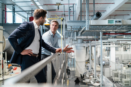Two businessmen talking in a modern factory photo