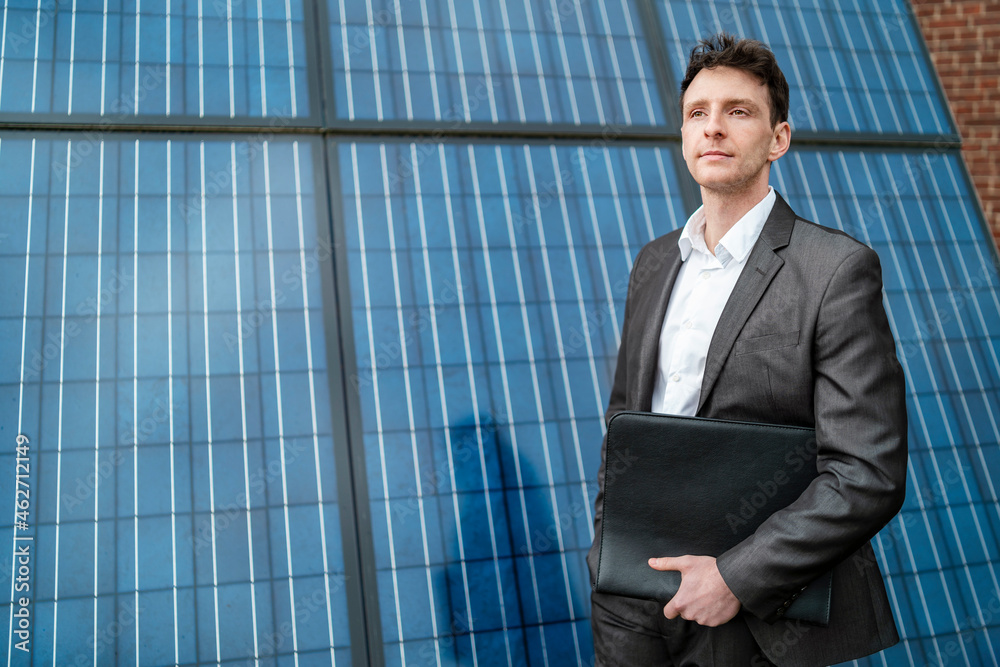 Businessman holding folder standing in front of solar panels Businessman holding folder standing in front of solar panels