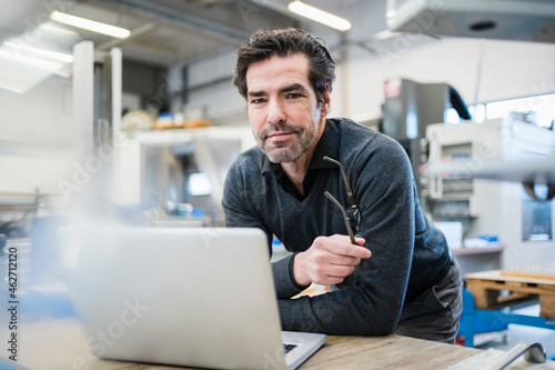 Portrait of businessman using laptop in a factory photo
